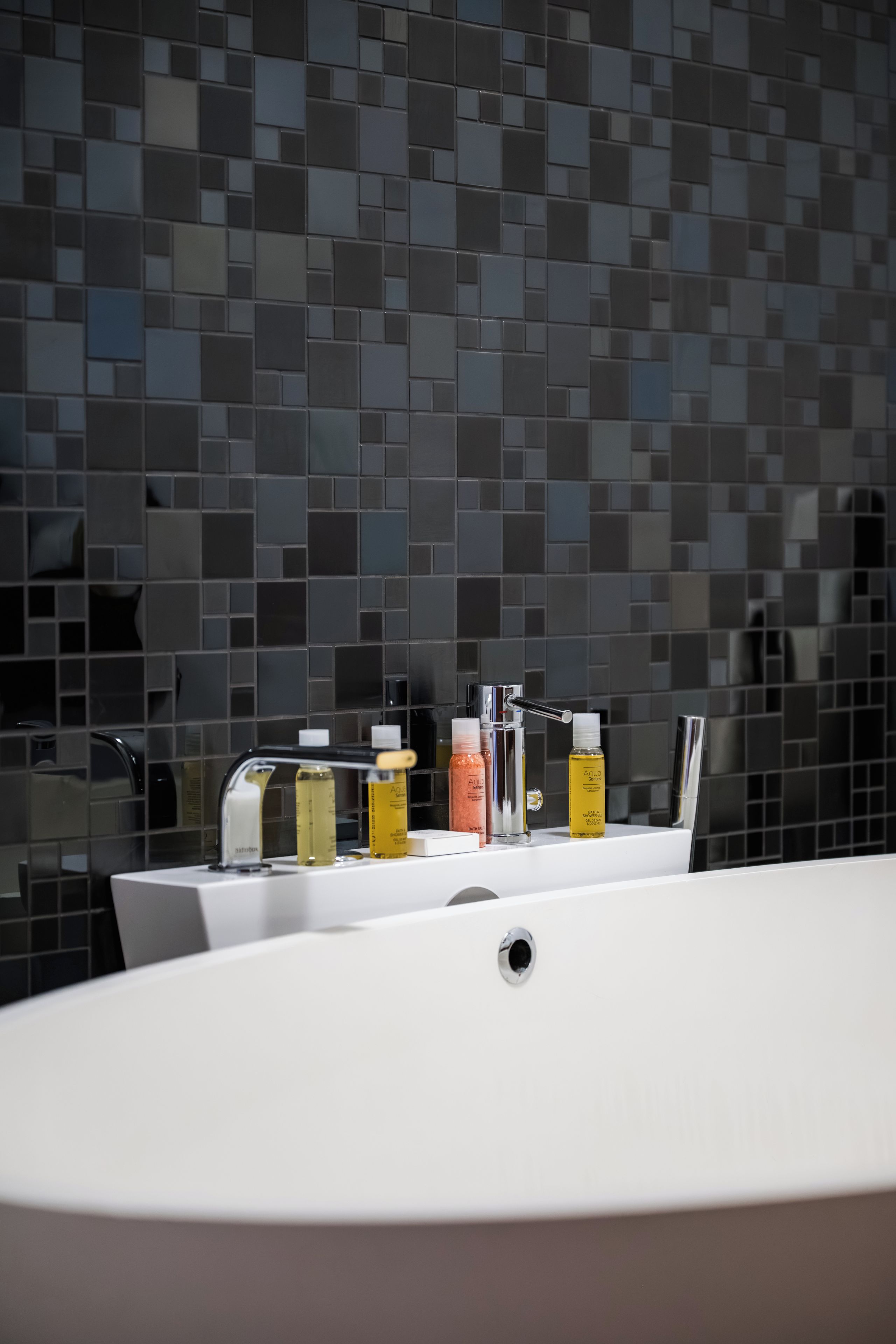 A bathroom with a white sink, a mirror, and toiletries on the counter.