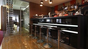 Un área de bar moderna con un botellero, taburetes y un gran cuenco de metal.