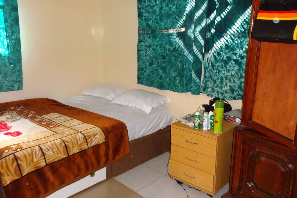 A bedroom with a bed, a nightstand, and a dresser.