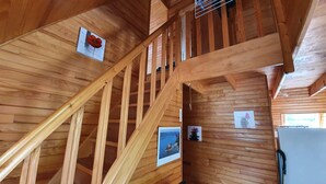 A wooden staircase with a metal handrail, wooden walls, and a ceiling fan. - Chalet between lakes and mountains, unlimited fishing (Beaulieu)