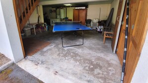 A room with a ping pong table, a staircase, and a wooden door. - Chalet between lakes and mountains, unlimited fishing (Beaulieu)