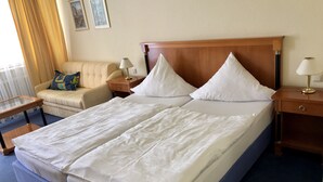 A hotel room with a double bed, a sofa, a nightstand with a lamp, and a small table. - Hotel Lust (Hoechst im Odenwald)