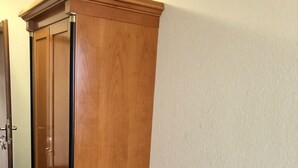 A corner room with a wooden wardrobe and a small wooden bench against the wall. - Hotel Lust (Hoechst im Odenwald)