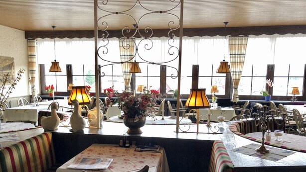 A restaurant with a cozy interior, featuring striped benches, tables with floral tablecloths, and decorative lamps. - Hotel Lust (Hoechst im Odenwald)