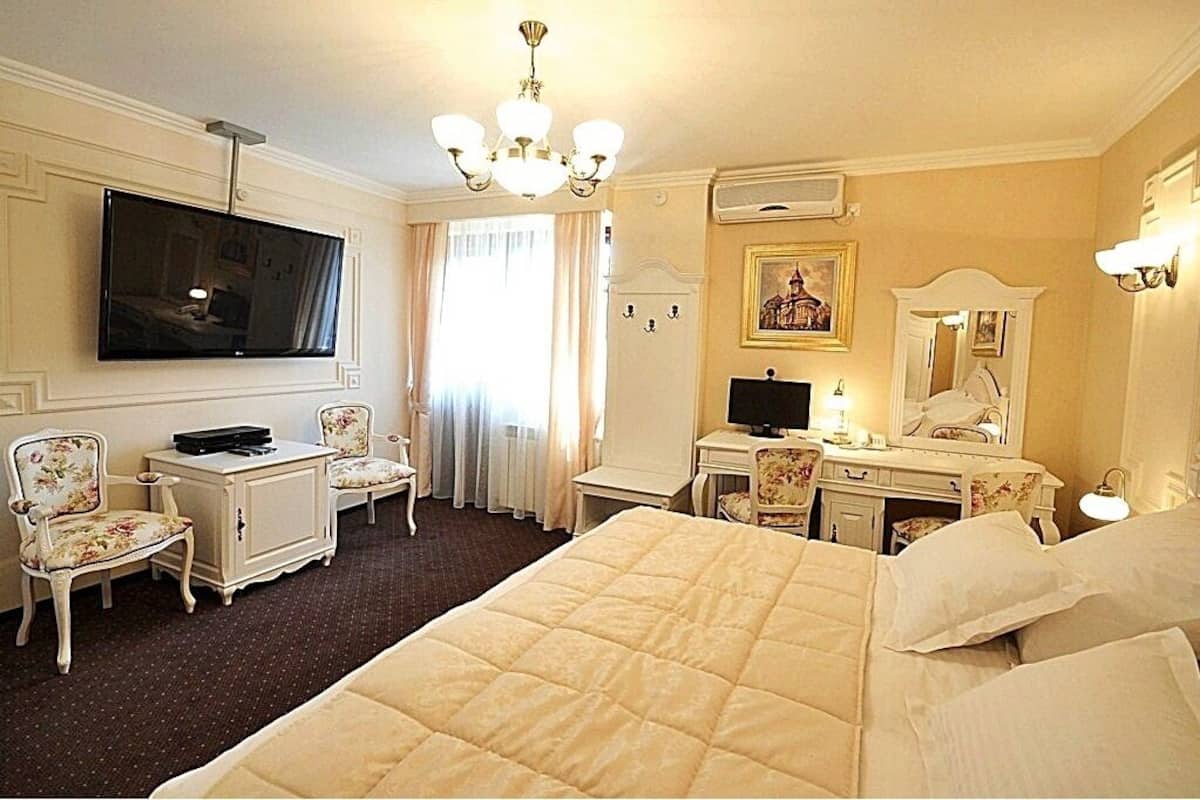 Habitación de hotel con una cama grande, un escritorio con computadora, televisor, una silla y un aparador.