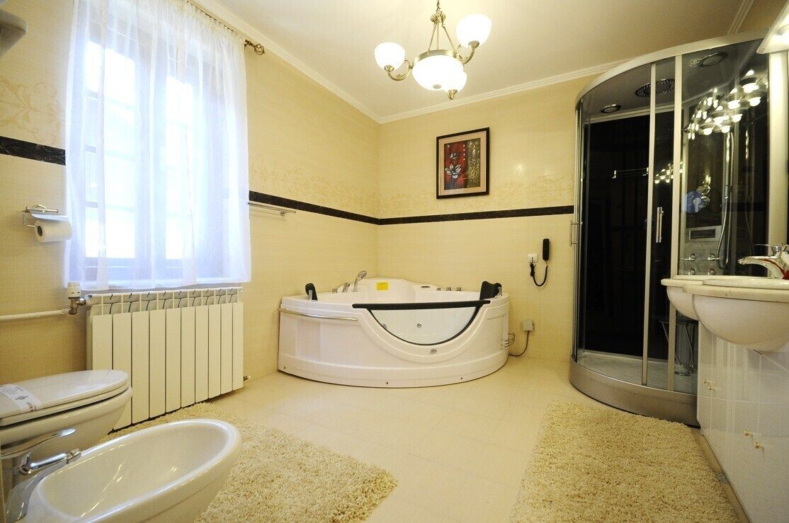 A bathroom with a bathtub, toilet, bidet, and a glass-enclosed shower.