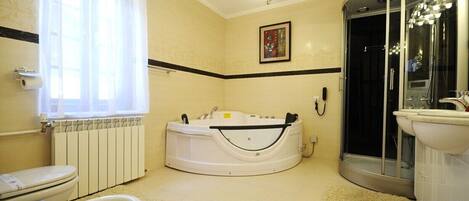 A bathroom with a bathtub, toilet, bidet, and a glass-enclosed shower.