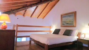 A bedroom with a wooden bed, a nightstand, a lamp, and a painting on the wall.