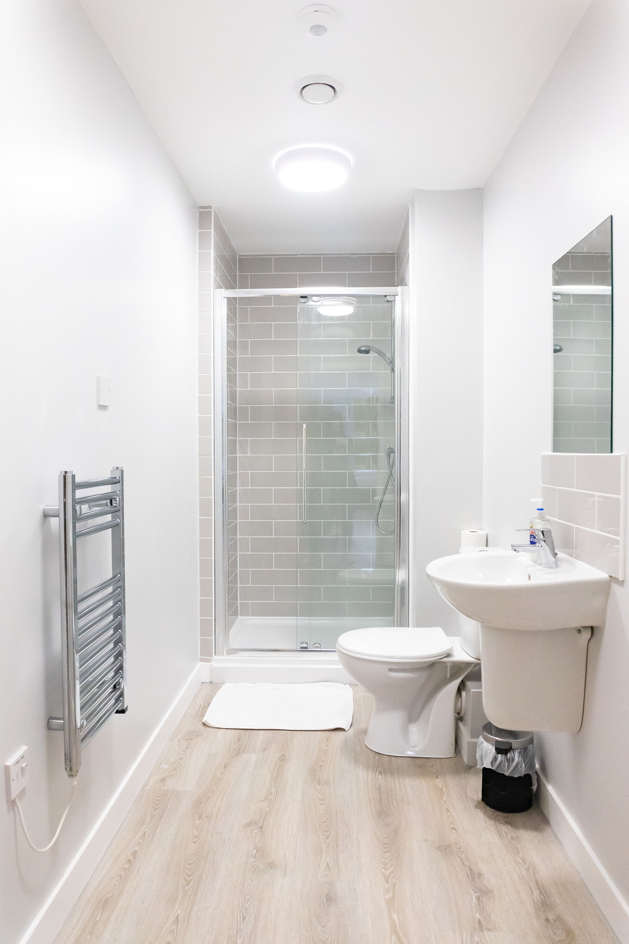 A modern bathroom with a glass-enclosed shower, a white sink, and a toilet.