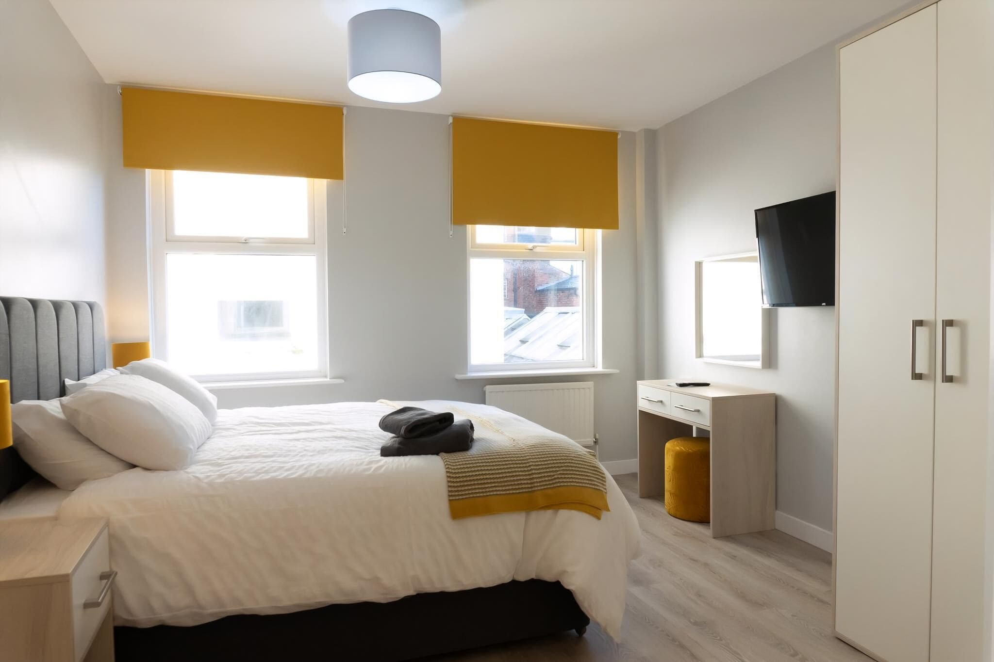 Une chambre à coucher moderne avec un lit, une table de chevet et un téléviseur fixé au mur.
