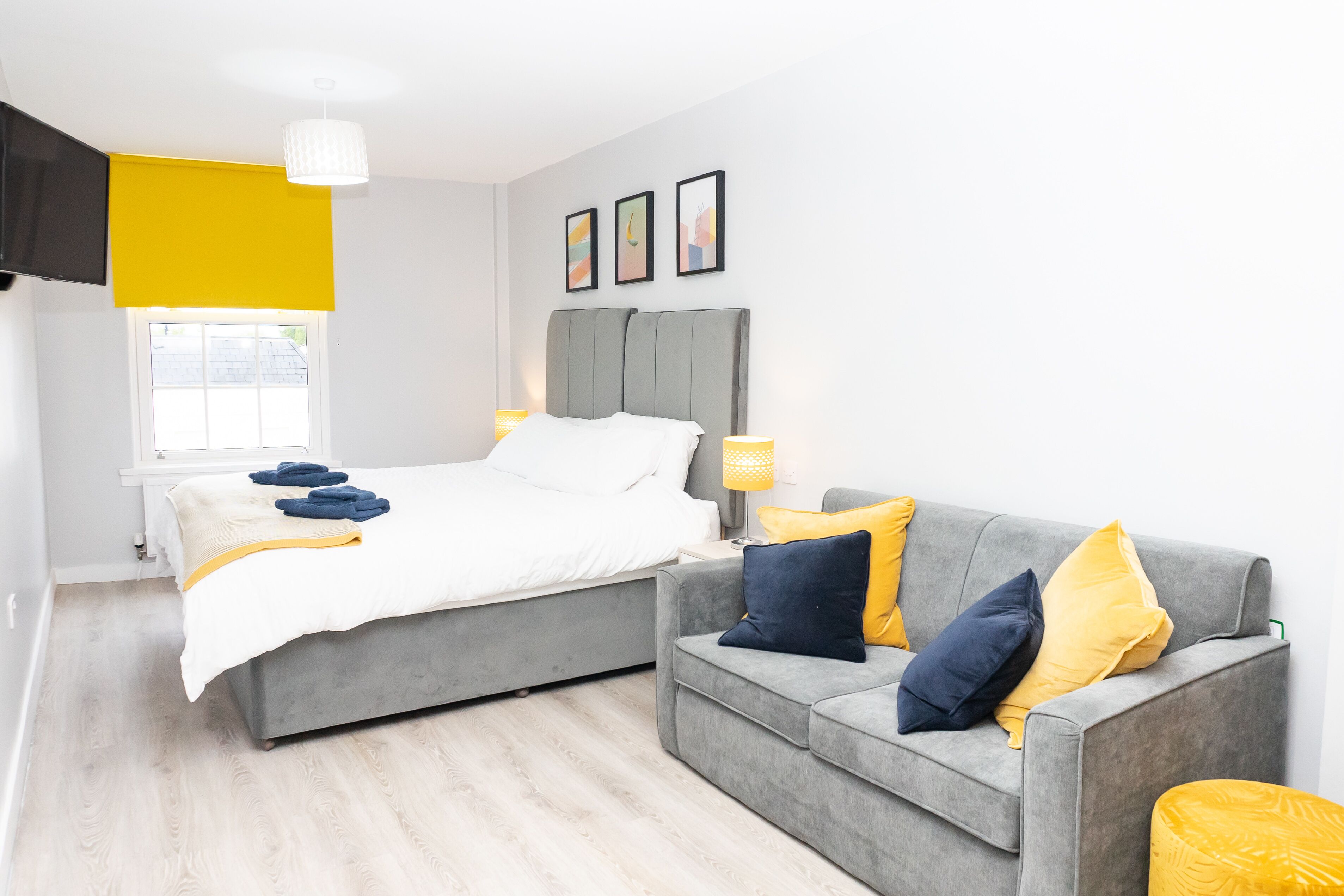 Un dormitorio moderno con cama, un sofá gris y una ventana.
