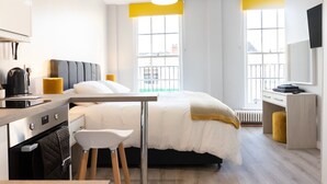 A modern hotel room with a bed, a desk, a chair, a kettle, and a radiator. - Spa Court (Cheltenham)