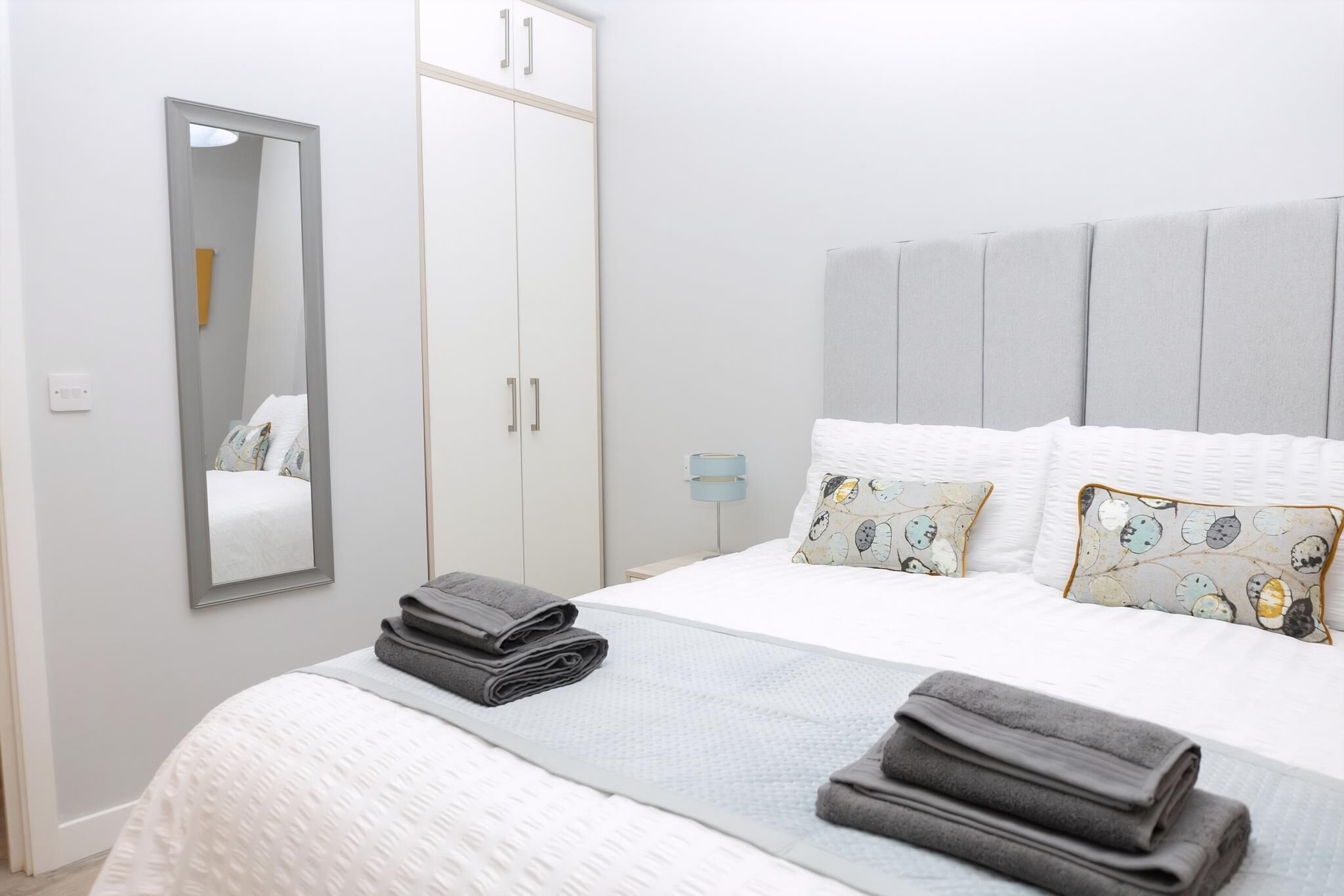 Ein Schlafzimmer mit Bett, Kleiderschrank, Spiegel und Nachttisch.