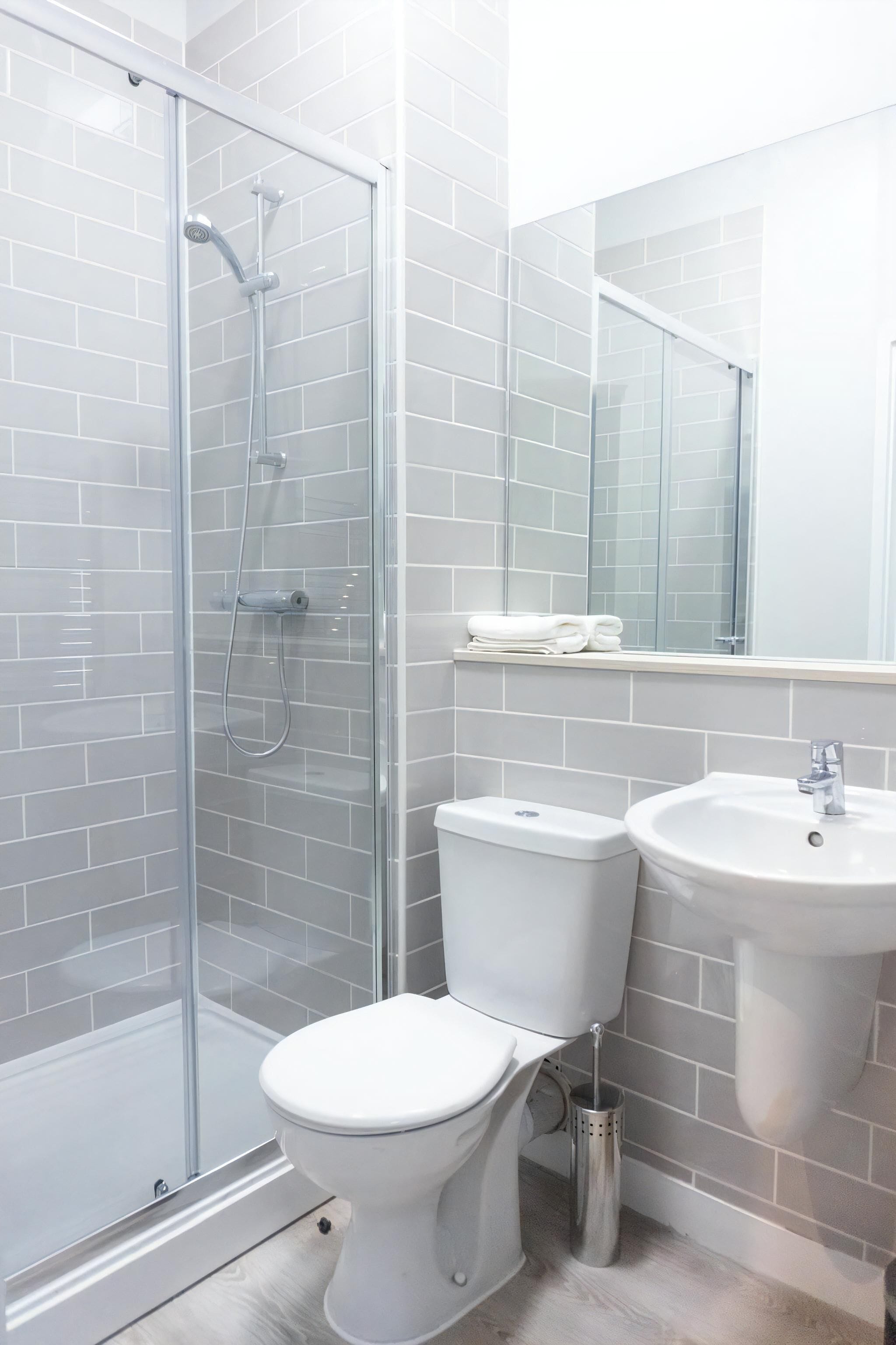 A bathroom with a glass-enclosed shower, a toilet, and a sink.