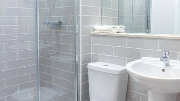 A bathroom with a glass-enclosed shower, a toilet, and a sink.