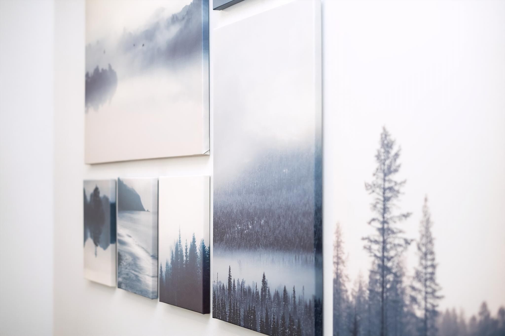 Una pared con cuatro cuadros que muestran paisajes tranquilos.