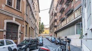 Una stretta via cittadina fiancheggiata da auto parcheggiate e palazzi.