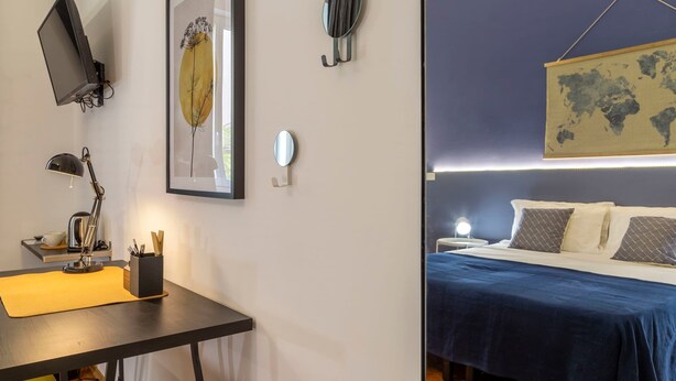 Una camera da letto con un letto, una scrivania con una lampada, una mappa del mondo e un quadro appeso al muro.