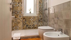 Un bagno con piastrelle decorate, un WC, un bidet e un lavandino.