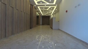 Un pasillo con un diseño moderno de techo, paneles de madera en las paredes y un mostrador de recepción.