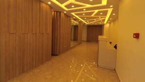 Un pasillo con paneles de madera, iluminación empotrada y suelo de mármol.