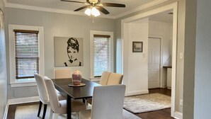 A dining area with a table, chairs, a vase, and a ceiling fan.