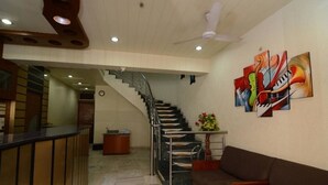 Un vestíbulo con una escalera, una recepción y un sofá.