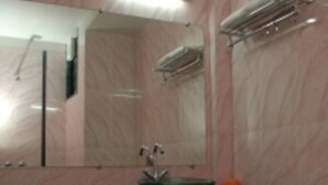 Un baño con lavamanos de mármol, un espejo y un perchero para toallas.