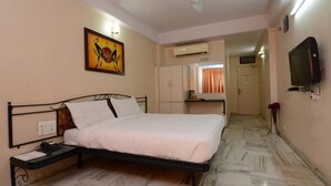 Un dormitorio con cama, ventilador de techo, aire acondicionado, televisor y un cuadro en la pared.