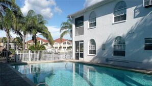 A swimming pool with a white building in the background. - Beautiful open sunny Condo on waterfront dock with Gulf access in  Cape Coral Fl (Cape Coral)