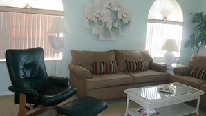 A living room with a beige sofa, a black leather chair, and a glass coffee table. - Beautiful open sunny Condo on waterfront dock with Gulf access in  Cape Coral Fl (Cape Coral)