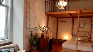 A cozy room with a loft bed, a sofa, a small table with a plant, and a lamp. - Lisbon Calling (Lisbon)
