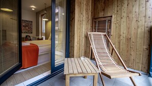 A wooden interior with a bed, a table, and a wooden ladder.
