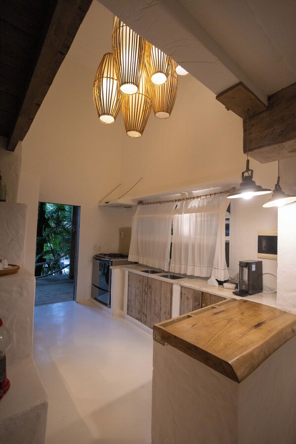Uma cozinha com armários de madeira, bancada e luminárias pendentes.