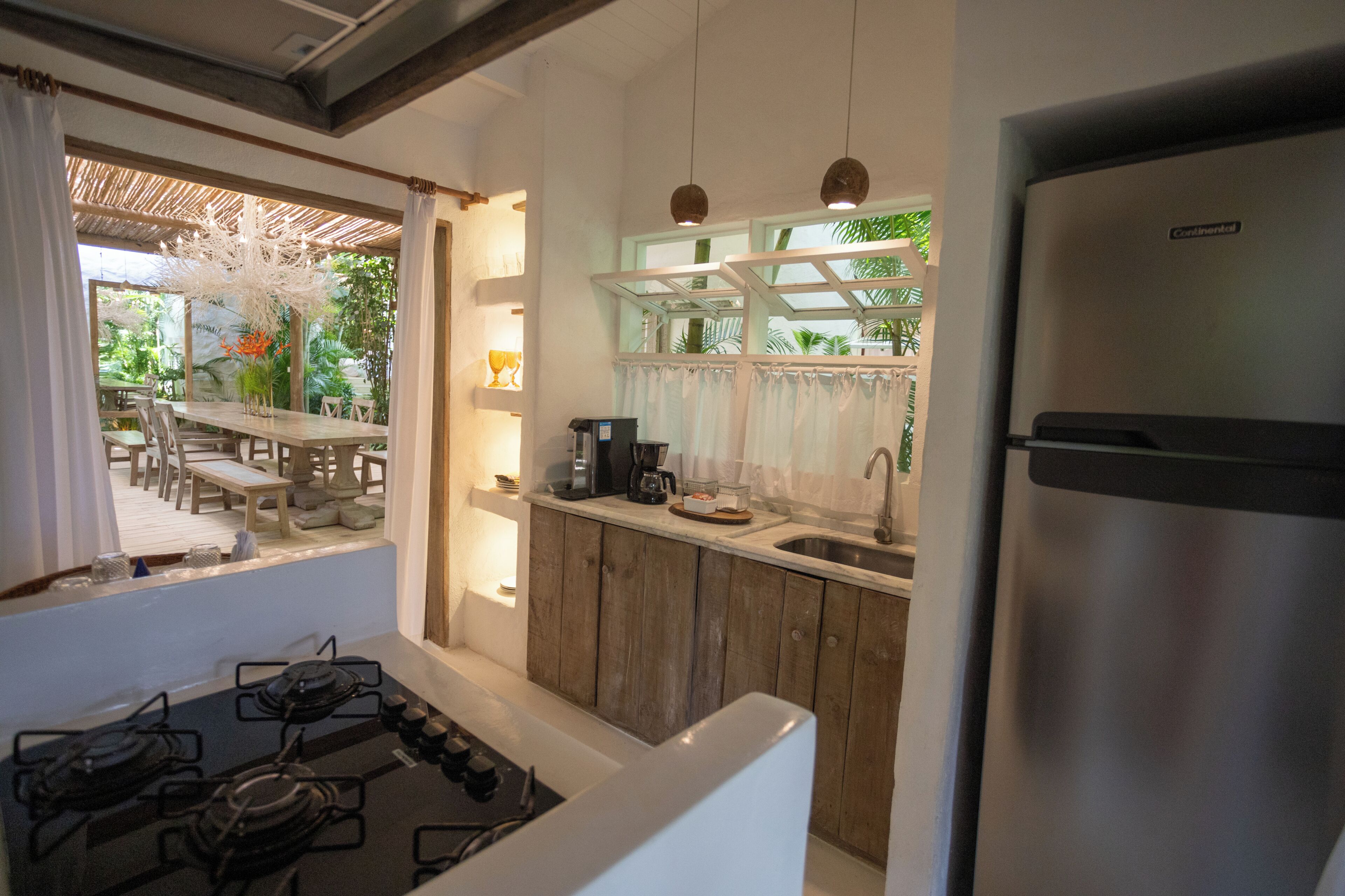 A kitchen with a gas stove, wooden cabinets, a stainless steel refrigerator, and a window overlooking a dining area.