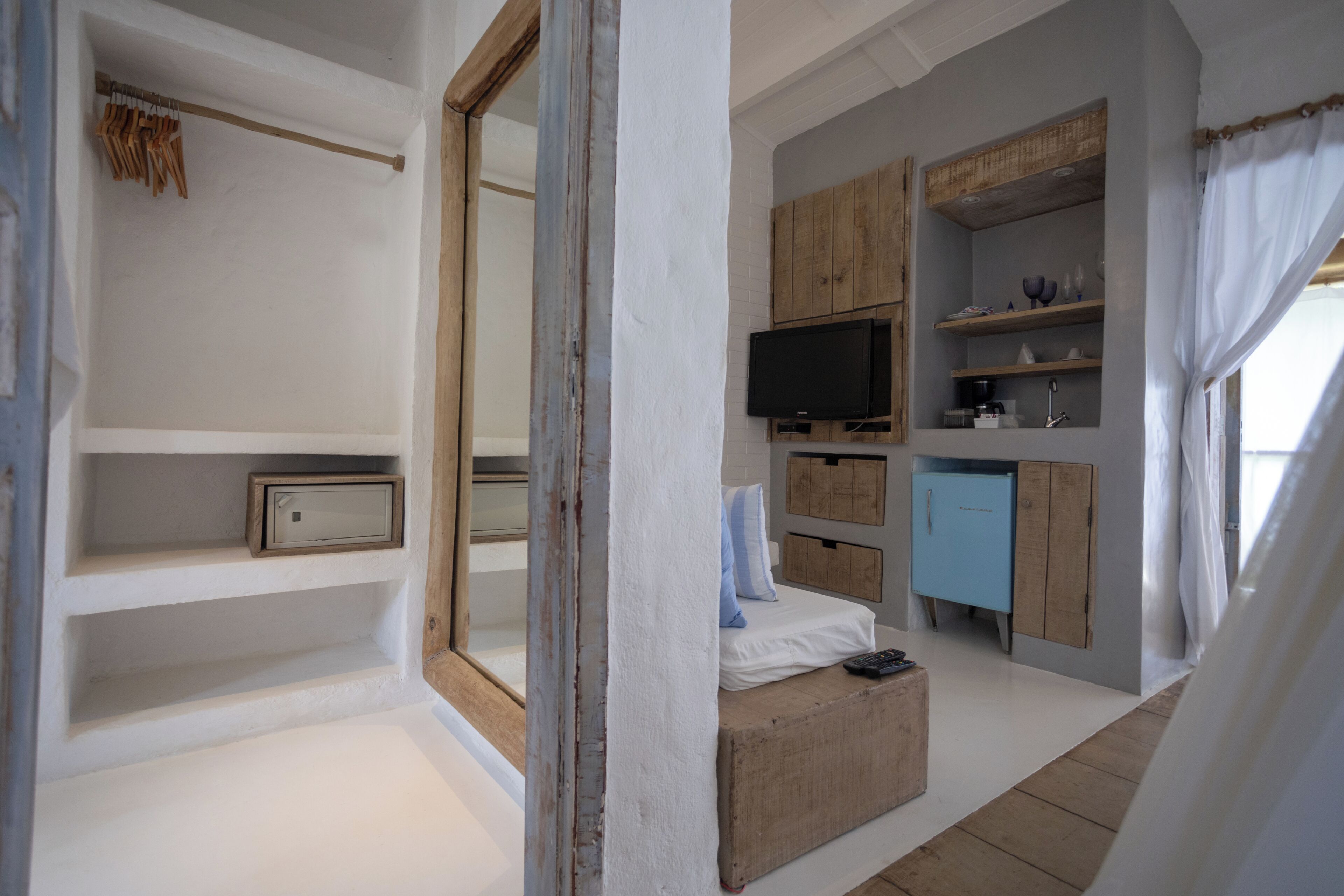 A bedroom with a bed, a television, wooden cabinets, and a small table.