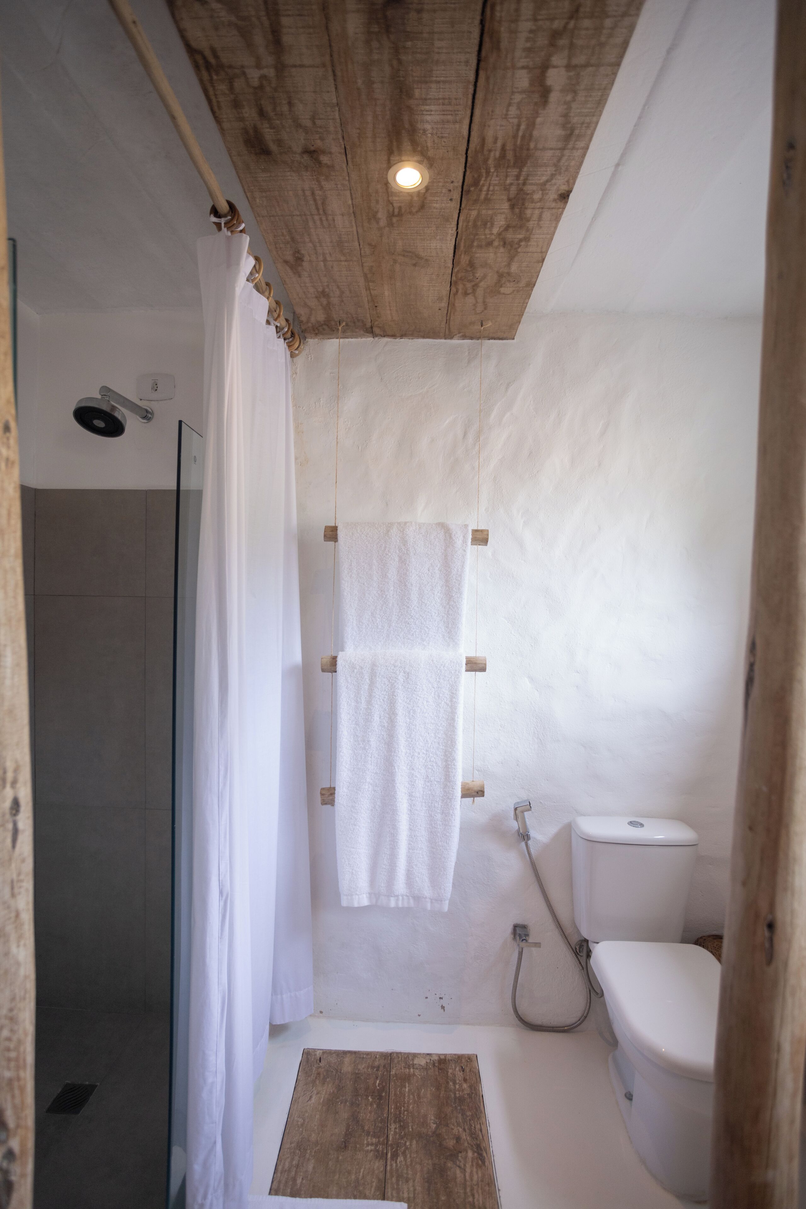 Un baño con ducha, inodoro y techo de madera.