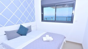 A neatly made bed with a quilted bedspread, a pillow, and a rolled towel. - Domos Tiberias (Tiberias)