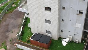 A multi-story building with a flat facade, multiple windows, and a small rooftop structure. - Domos Tiberias (Tiberias)
