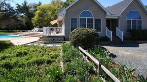 Uma casa de dois andares com piscina, varanda coberta e um jardim bem cuidado.