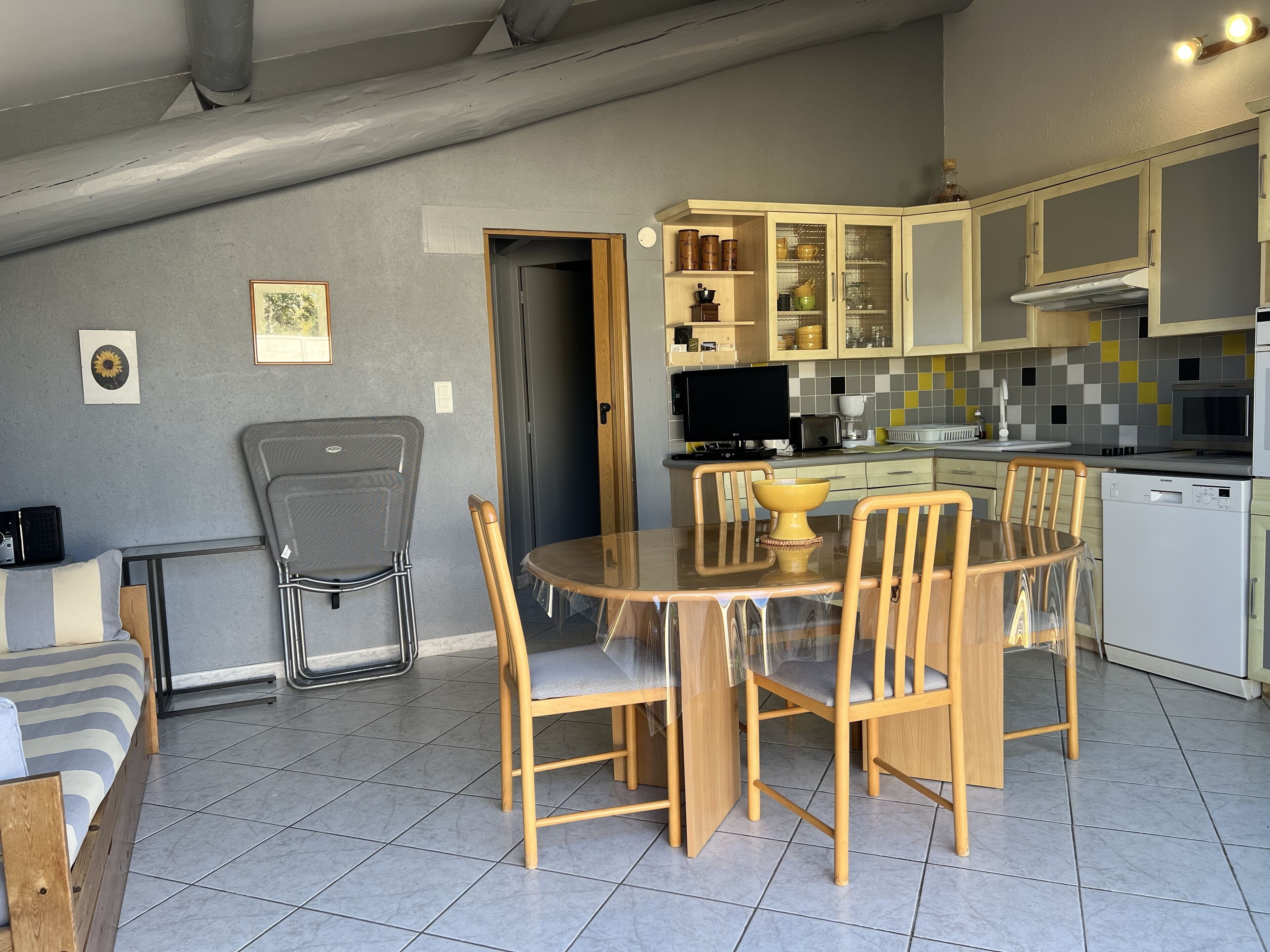 Una cocina moderna con zona de comedor, que incluye una mesa y sillas de madera, horno empotrado y microondas.