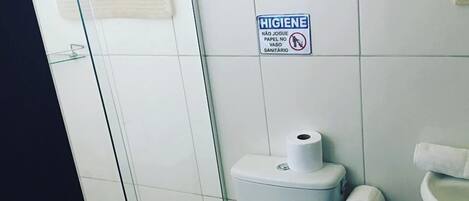 Un baño con inodoro, secamanos, lavamanos y un cartel de higiene.