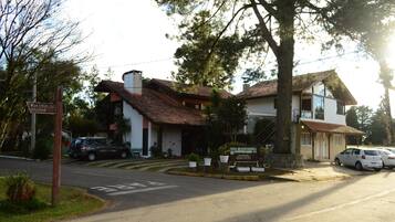 Un edificio de dos plantas con techo de tejas, un cartel y un estacionamiento con coches.