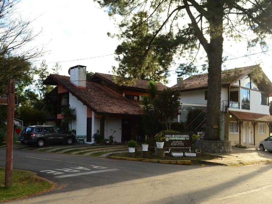 Un edificio de dos plantas con techo de tejas, un cartel y un estacionamiento con coches.