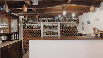 A bar with wooden shelves and a wine rack, featuring various bottles and glassware.