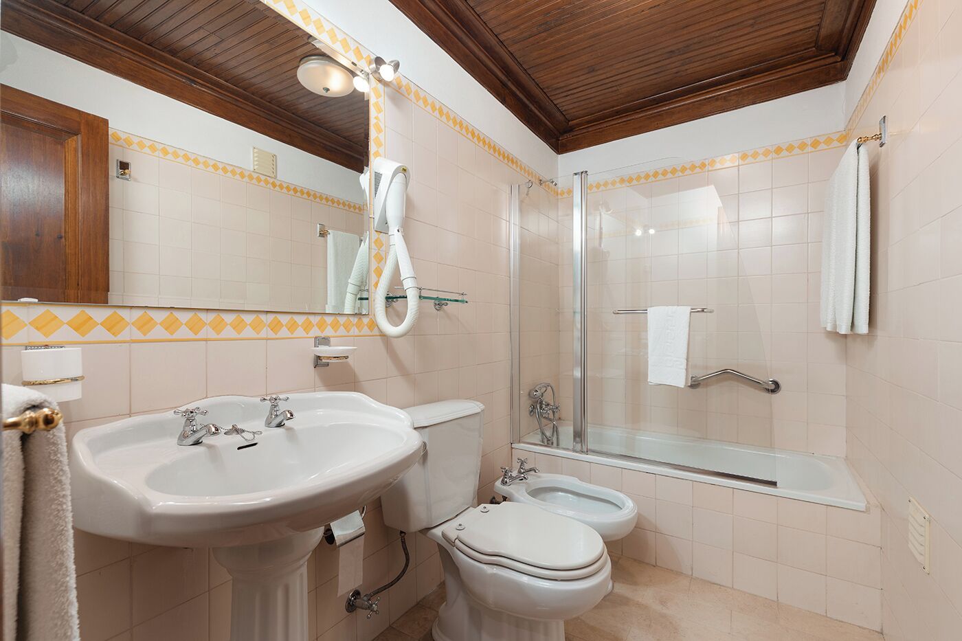 A bathroom with a sink, toilet, bidet, and a shower area.