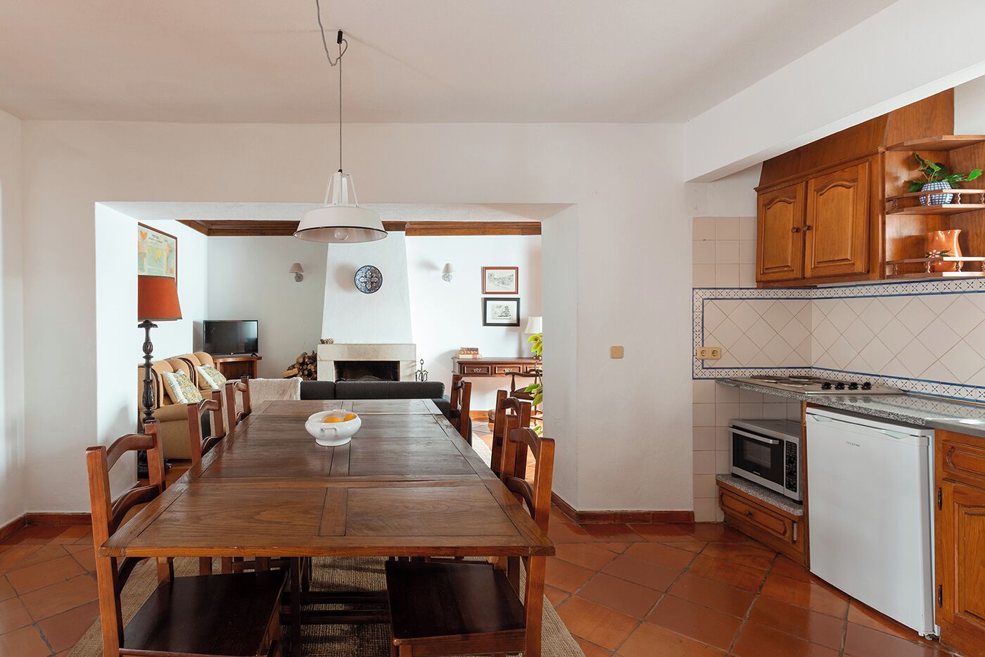 A spacious dining area with a wooden table and chairs, a kitchen with wooden cabinets and appliances, and a living area with a sofa and fireplace.