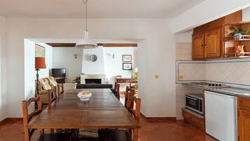 A spacious dining area with a wooden table and chairs, a kitchen with wooden cabinets and appliances, and a living area with a sofa and fireplace.