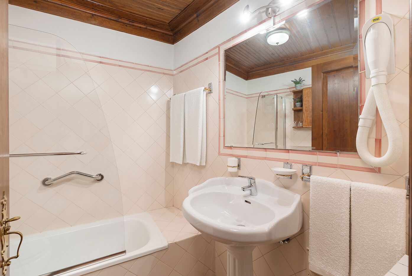 Un bagno con vasca, lavandino, specchio e portasciugamani.