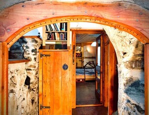 A rustic wooden room with a stone wall, a wooden door, and a bookshelf filled with books. - Unique Fairytale Farmhouse Near Galway (Corrandulla)